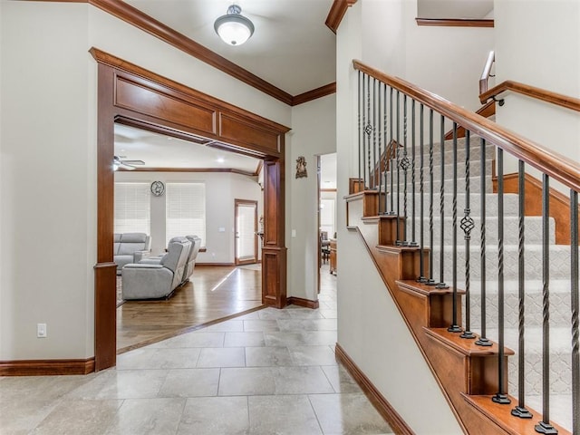 stairs featuring tile patterned floors, baseboards, ornamental molding, and a ceiling fan