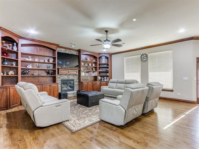 living room featuring baseboards, a stone fireplace, crown molding, a ceiling fan, and wood finished floors