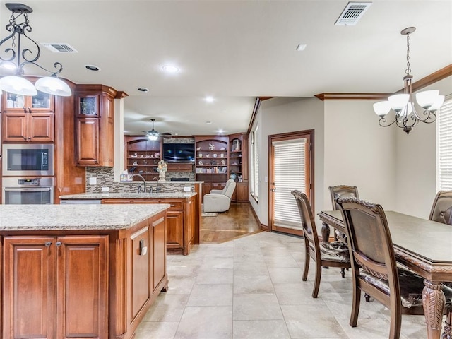 kitchen with open floor plan, visible vents, brown cabinets, stainless steel appliances, and ceiling fan with notable chandelier