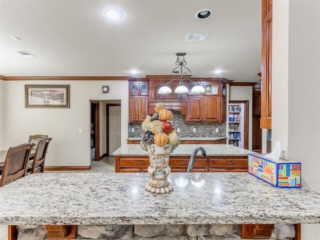 kitchen featuring glass insert cabinets, visible vents, crown molding, and backsplash