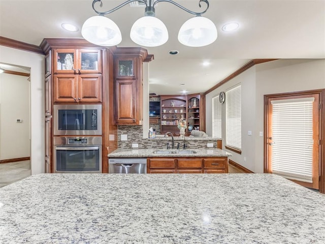 kitchen with baseboards, a sink, crown molding, stainless steel appliances, and light stone counters