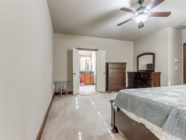 bedroom featuring baseboards, a ceiling fan, ensuite bath, and light carpet