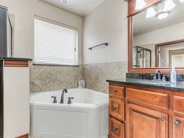 full bath featuring a jetted tub, a stall shower, and vanity