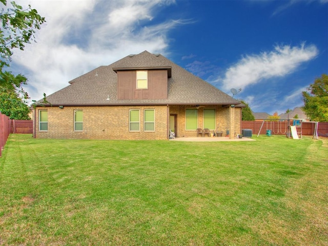 rear view of property featuring a patio area, a yard, a fenced backyard, a playground, and brick siding