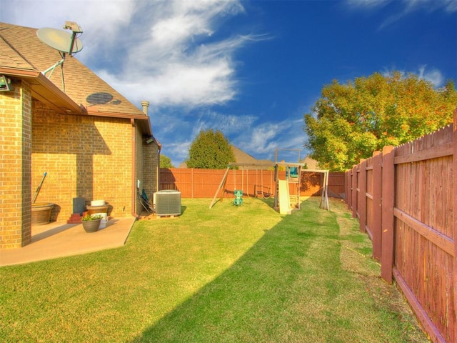 view of yard with central air condition unit, a fenced backyard, and a playground