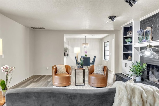 10908 Bel Air Pl, Oklahoma City, OK 73120 - living area with a notable chandelier, wood finished floors, a textured ceiling, and visible vents
