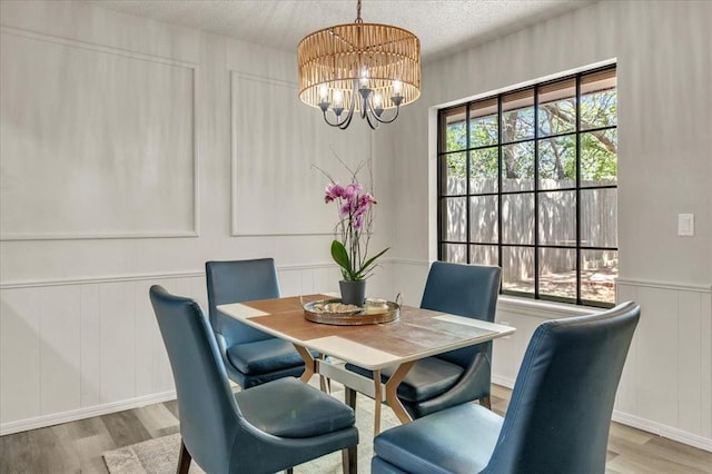 10908 Bel Air Pl, Oklahoma City, OK 73120 - dining room featuring wood finished floors, a textured ceiling, a chandelier, and a decorative wall