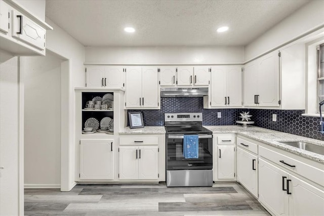 10908 Bel Air Pl, Oklahoma City, OK 73120 - kitchen featuring white cabinets, under cabinet range hood, a sink, tasteful backsplash, and stainless steel electric range oven