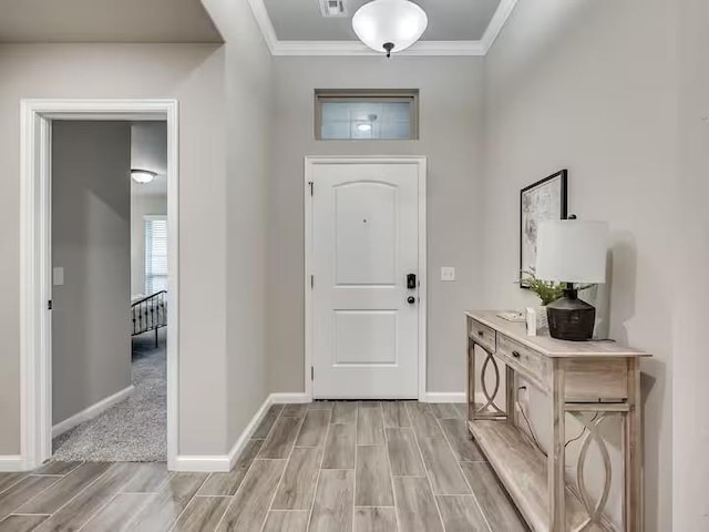 foyer with visible vents, baseboards, wood finish floors, and crown molding