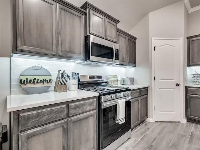 kitchen featuring decorative backsplash, light countertops, dark brown cabinetry, and appliances with stainless steel finishes