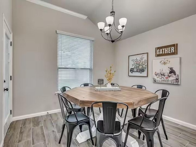 dining space featuring ornamental molding, baseboards, a notable chandelier, and wood tiled floor