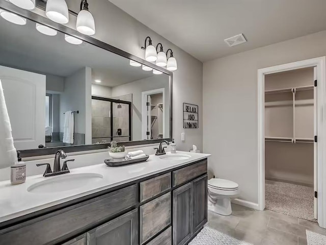 bathroom featuring a shower stall, a spacious closet, a sink, and visible vents