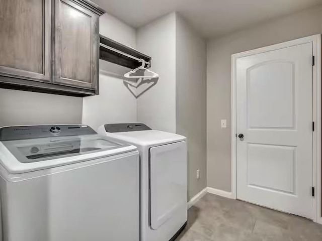 laundry room with washing machine and clothes dryer, cabinet space, and baseboards