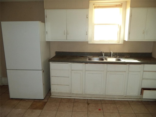 708 E Harrison Ave, Guthrie, OK 73044 - kitchen with dark countertops, a sink, white cabinetry, and freestanding refrigerator