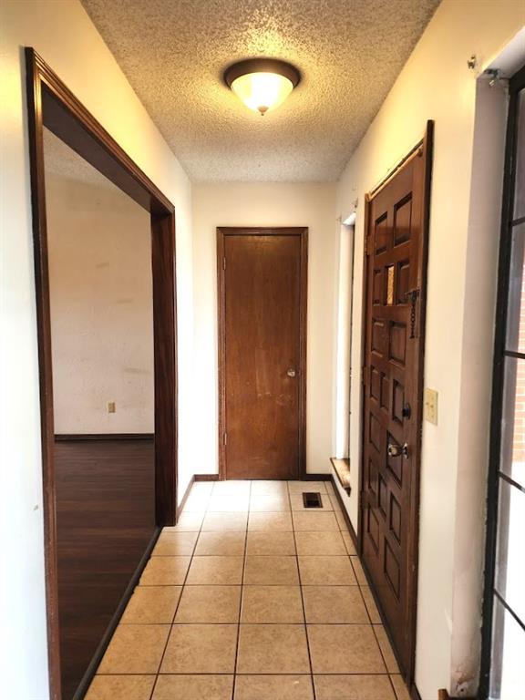 613 NE 15th St, Moore, OK 73160 - corridor featuring a textured ceiling, light tile patterned floors, and baseboards