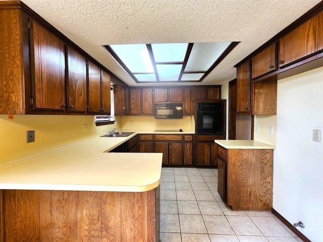 613 NE 15th St, Moore, OK 73160 - kitchen with black appliances, light countertops, a textured ceiling, a sink, and a peninsula