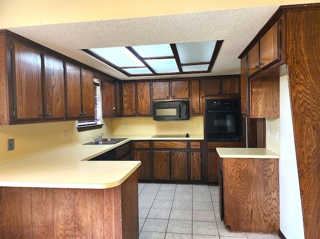 613 NE 15th St, Moore, OK 73160 - kitchen featuring black appliances, light countertops, a sink, a peninsula, and a textured ceiling