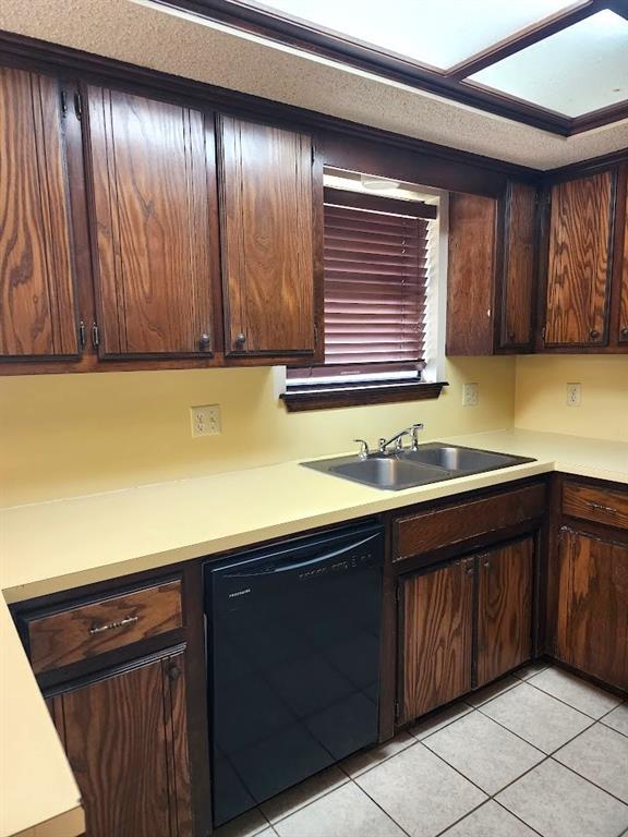 613 NE 15th St, Moore, OK 73160 - kitchen featuring black dishwasher, a sink, light tile patterned flooring, and light countertops