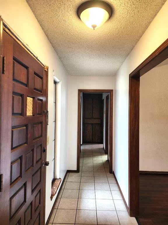 613 NE 15th St, Moore, OK 73160 - hall with a textured ceiling, light tile patterned floors, and baseboards