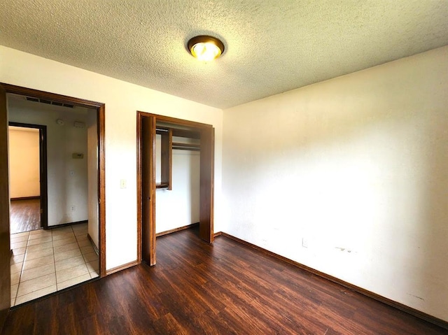 613 NE 15th St, Moore, OK 73160 - unfurnished bedroom with wood finished floors, a closet, baseboards, and a textured ceiling
