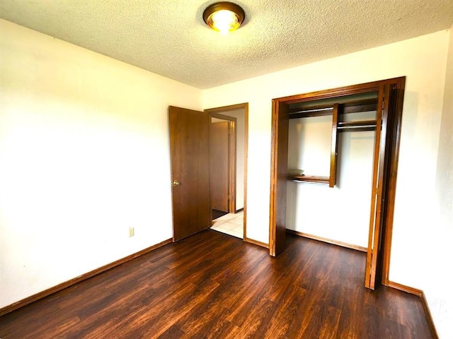 613 NE 15th St, Moore, OK 73160 - unfurnished bedroom with dark wood-type flooring, baseboards, a closet, and a textured ceiling