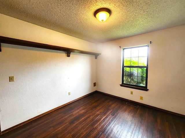 613 NE 15th St, Moore, OK 73160 - spare room with dark wood finished floors, a textured ceiling, and baseboards