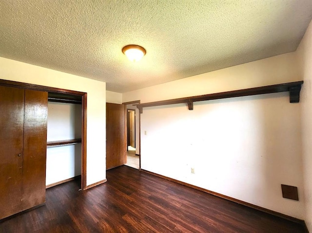613 NE 15th St, Moore, OK 73160 - unfurnished bedroom with dark wood-style flooring, a closet, baseboards, and a textured ceiling