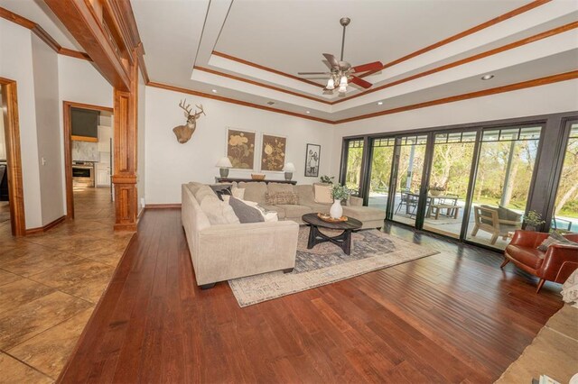 2400 Lost Lake Ln, Yukon, OK 73099 - living room featuring a ceiling fan, a raised ceiling, ornamental molding, wood-type flooring, and baseboards