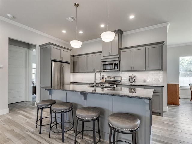 104 Rue De Montserrat, Norman, OK 73071 - kitchen with light wood-style flooring, dark stone countertops, gray cabinetry, and stainless steel appliances