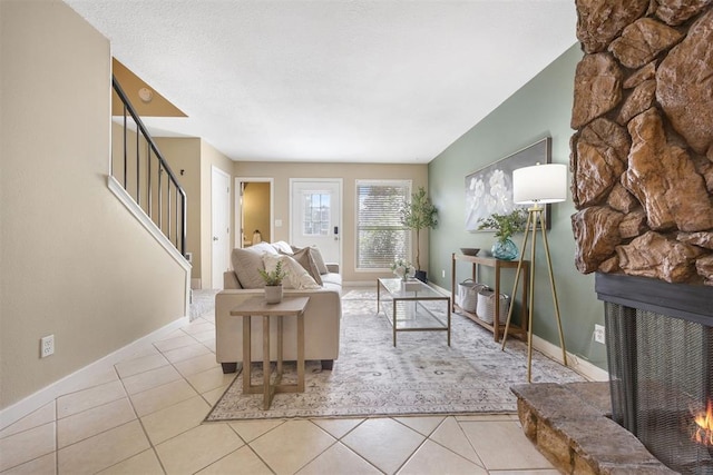 tiled living area featuring a fireplace, stairway, and baseboards