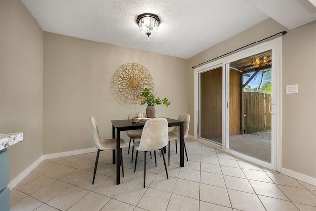 dining space featuring baseboards, a textured ceiling, and light tile patterned floors