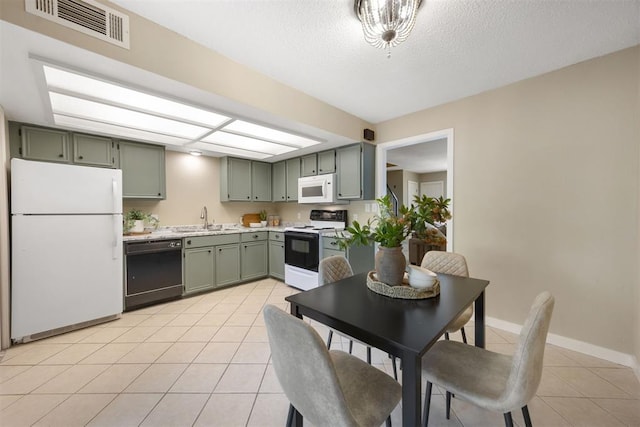kitchen with light countertops, visible vents, a sink, white appliances, and green cabinets