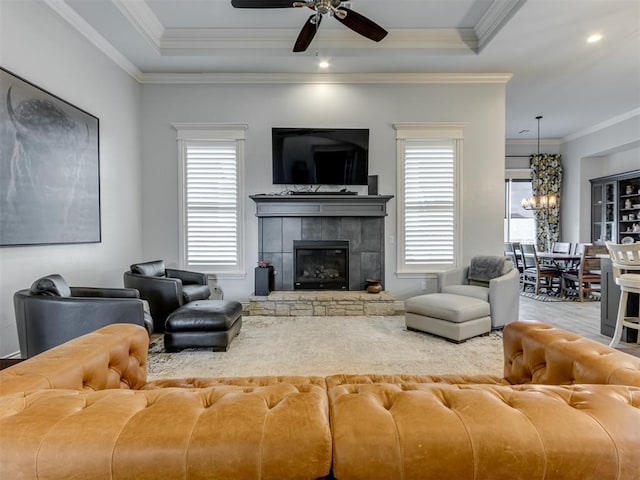 3108 Drake Crest Dr, Edmond, OK 73034 - living area with a tile fireplace, a tray ceiling, crown molding, wood finished floors, and ceiling fan with notable chandelier