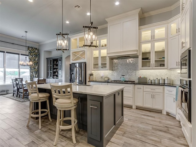 3108 Drake Crest Dr, Edmond, OK 73034 - kitchen with stainless steel appliances, decorative backsplash, a notable chandelier, ornamental molding, and an island with sink