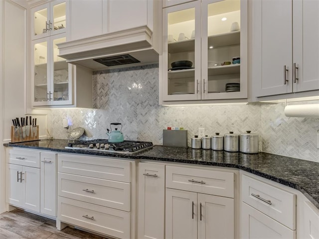 3108 Drake Crest Dr, Edmond, OK 73034 - kitchen with white cabinetry, custom range hood, stainless steel gas stovetop, and dark stone counters
