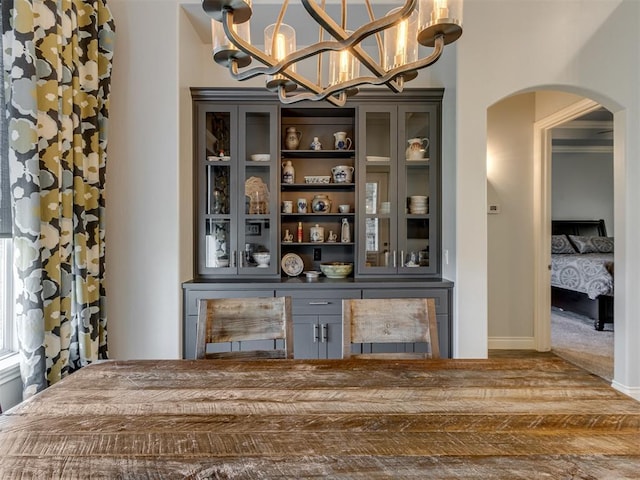 3108 Drake Crest Dr, Edmond, OK 73034 - bar with baseboards, arched walkways, decorative light fixtures, wood finished floors, and a notable chandelier