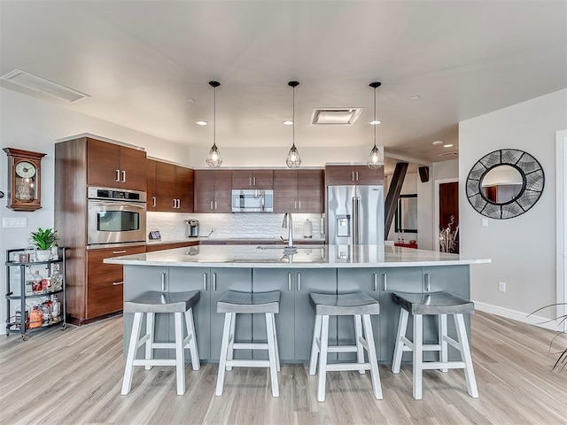 kitchen featuring a sink, decorative backsplash, light wood-type flooring, appliances with stainless steel finishes, and visible vents