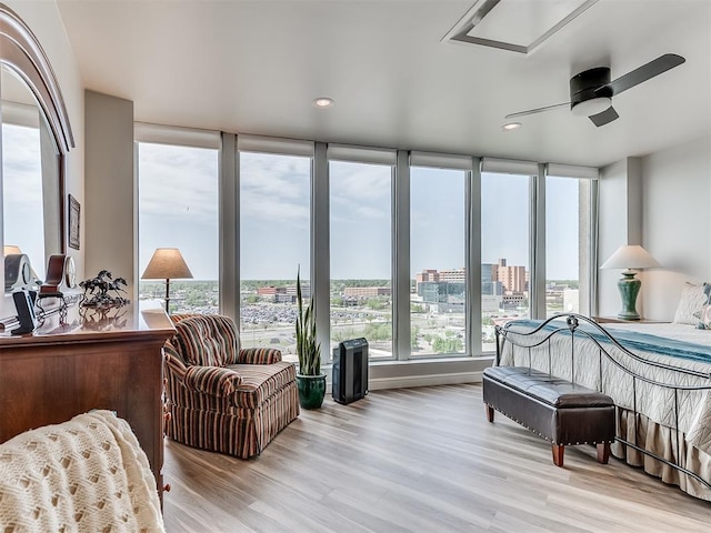bedroom featuring light wood finished floors, ceiling fan, recessed lighting, and a view of city