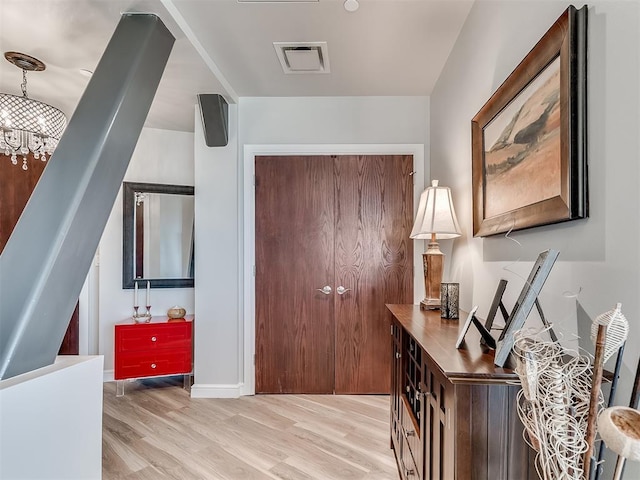 entryway featuring a notable chandelier, baseboards, visible vents, and light wood-style floors