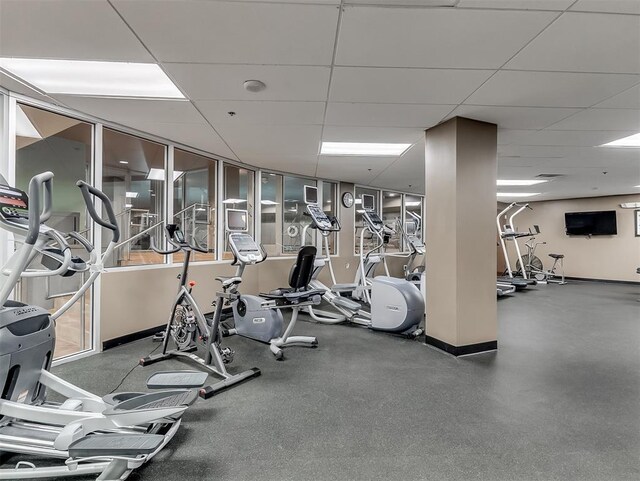 gym featuring baseboards and a drop ceiling