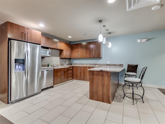 kitchen featuring a peninsula, pendant lighting, brown cabinets, a breakfast bar, and appliances with stainless steel finishes