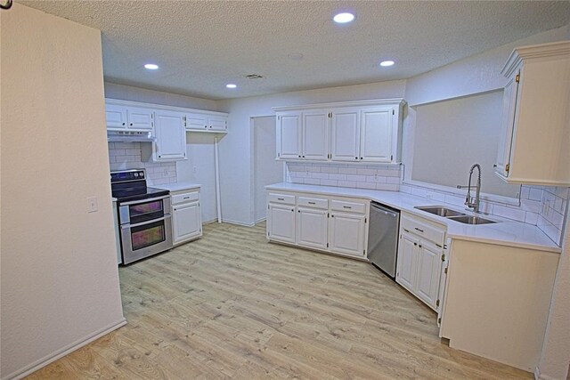 kitchen featuring tasteful backsplash, a sink, light countertops, under cabinet range hood, and stainless steel appliances