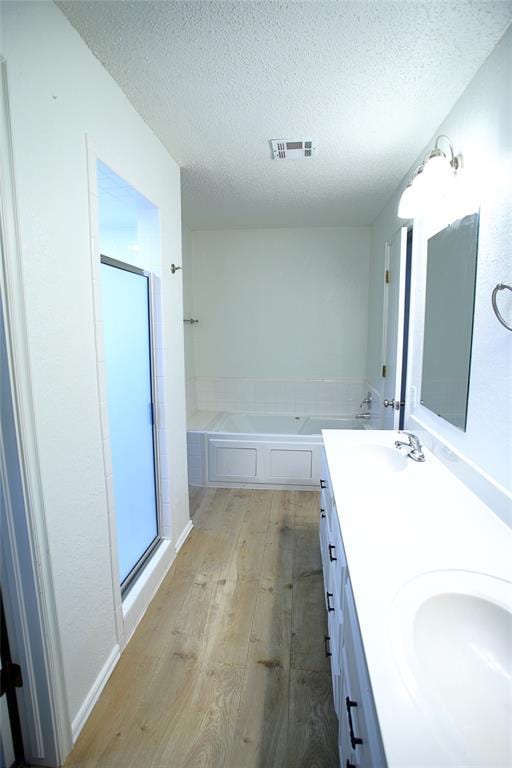 full bathroom featuring visible vents, a textured ceiling, a sink, and wood finished floors