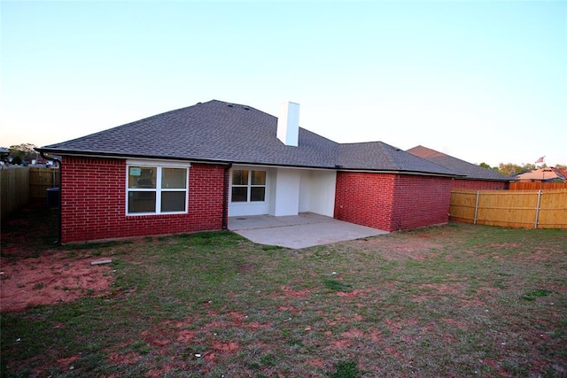 back of house featuring a patio, a yard, a fenced backyard, and brick siding