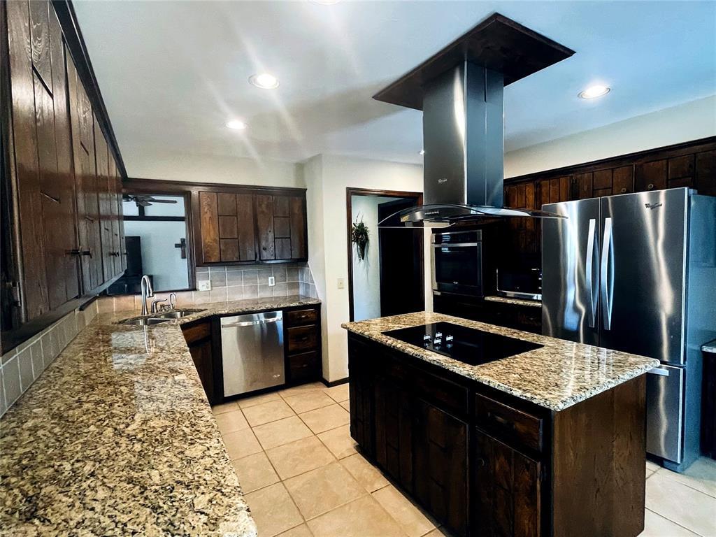kitchen featuring tasteful backsplash, dark brown cabinets, island exhaust hood, a sink, and stainless steel appliances