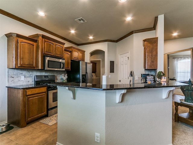 3515 Homesteaders Ln, Guthrie, OK 73044 - kitchen featuring stainless steel appliances, backsplash, visible vents, crown molding, and a breakfast bar area