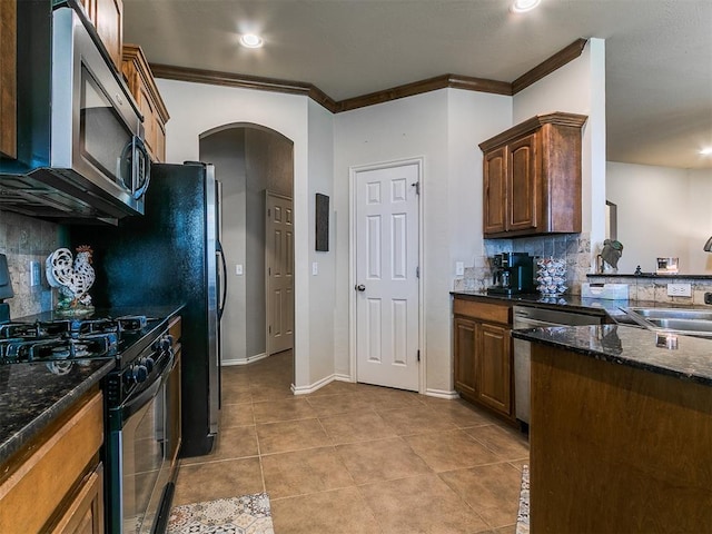 3515 Homesteaders Ln, Guthrie, OK 73044 - kitchen with stainless steel appliances, a sink, arched walkways, tasteful backsplash, and ornamental molding