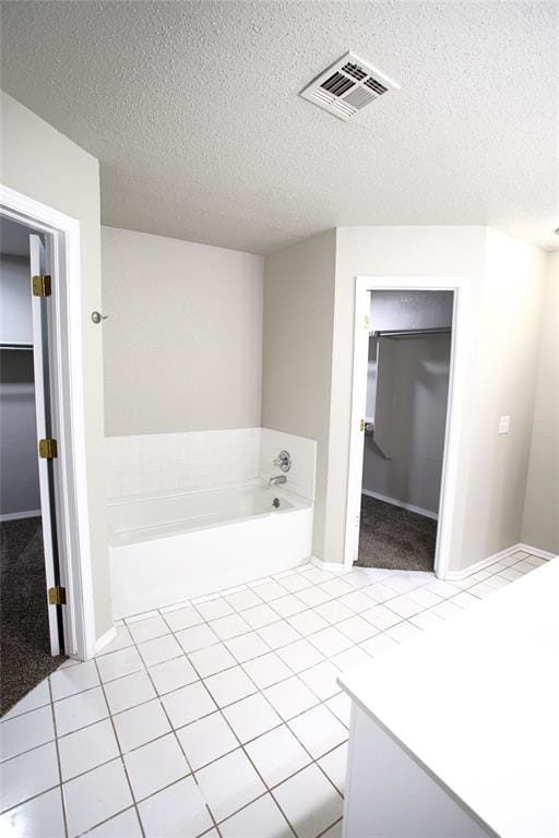 full bath with a textured ceiling, a garden tub, tile patterned flooring, and visible vents