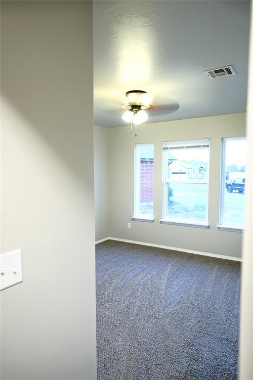 unfurnished room with carpet flooring, visible vents, baseboards, and a ceiling fan
