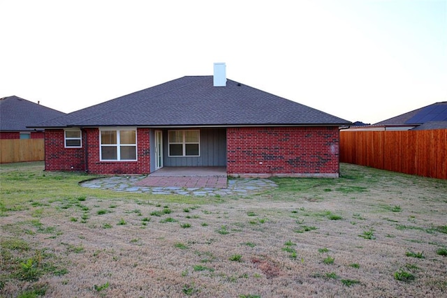 rear view of property featuring brick siding, a patio, a fenced backyard, and a lawn